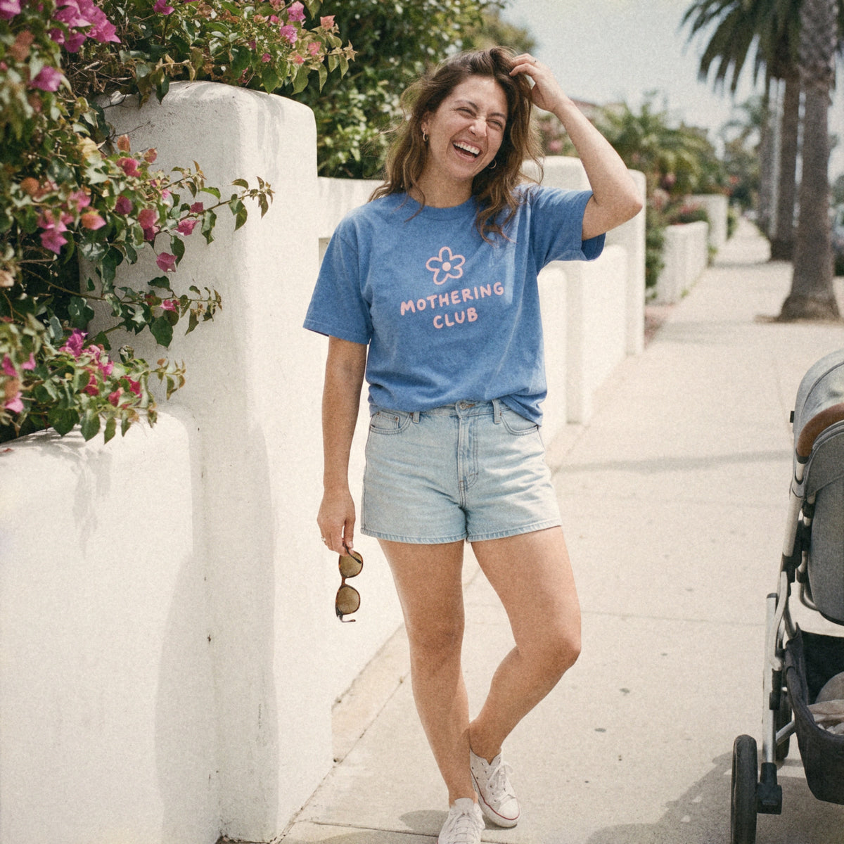 Mom in the Mothering Club Flower Tee laughing by a bougainvillea wall