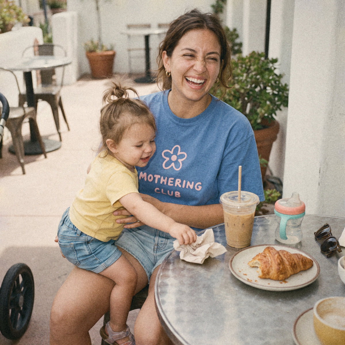 Mom in the Mothering Club Flower Tee at a café with her toddler