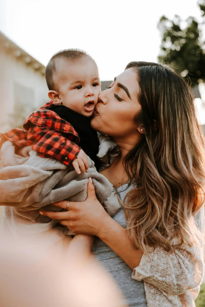 Woman kissing a baby she’s holding in her arms.