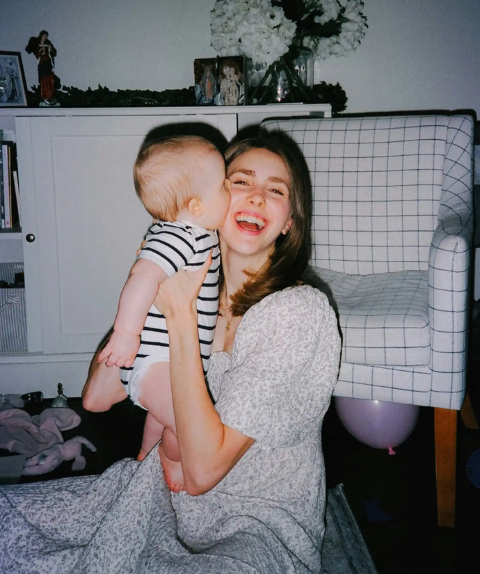 Woman holding and smiling with a baby.